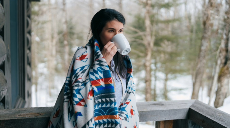 Femme buvant son café dans un chalet en montagne.